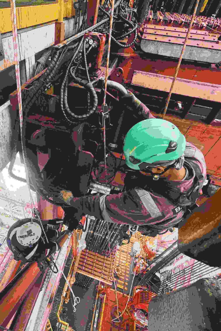 BTS rope access technician in harness working on an offshore rig