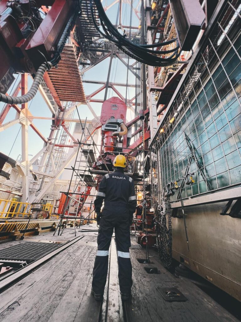 BTS technician walking on a drilling rig floor next to the derrick