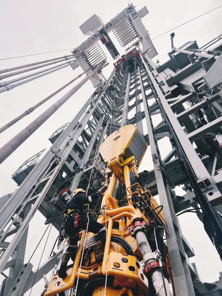 BTS rope access technician climbing the top drive inside a drilling derrick